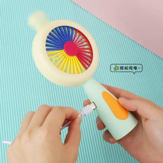 Colorful toy with a light on top, held by a hand against a light pink background.